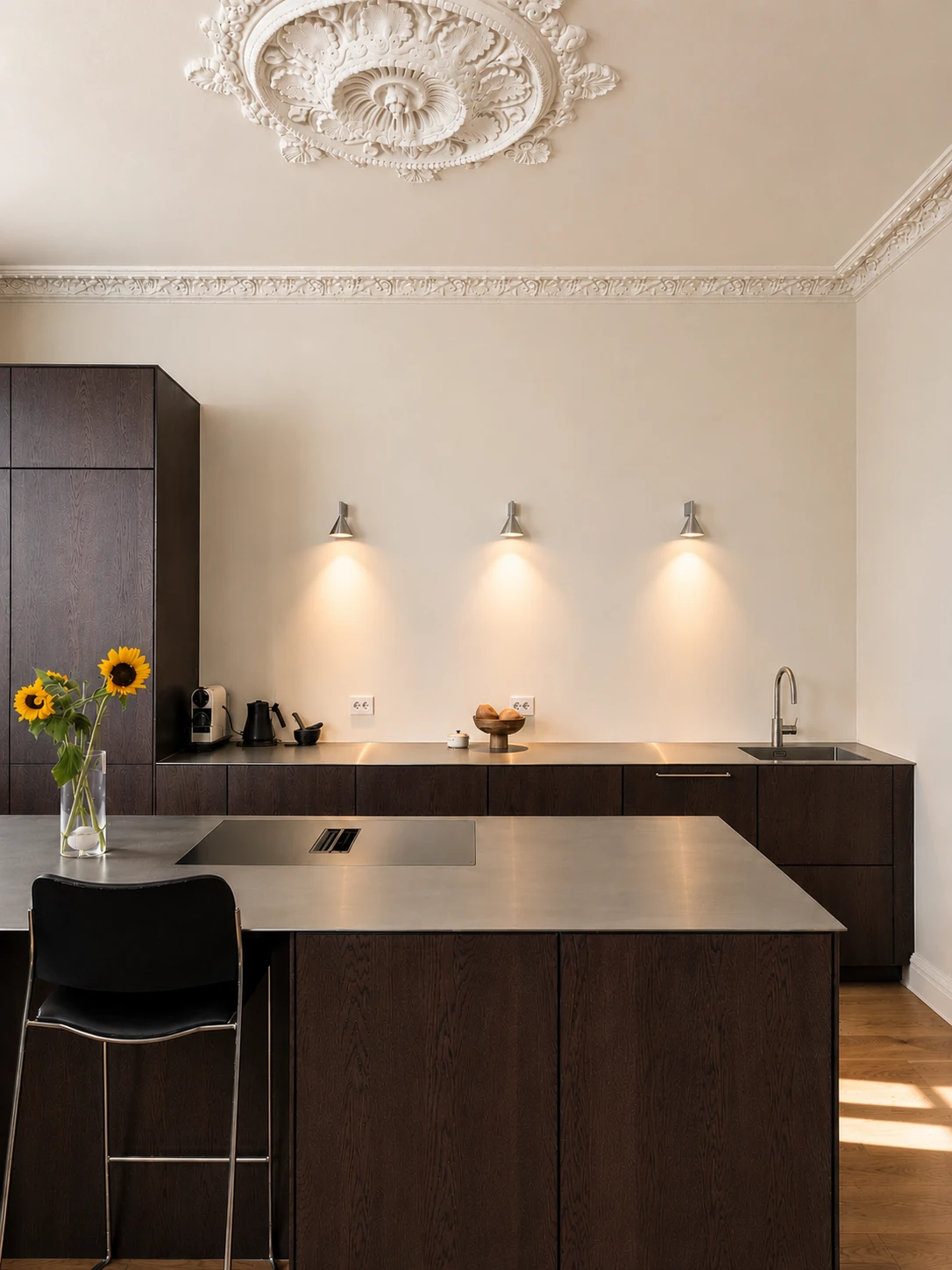Prosjekt 02 — Et moderne kjøkken med fronter i mørkt tre, rene linjer, kjøkkenøy og en elegant, tynn benkeplate i rustfritt stål.